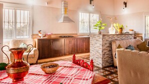 A spacious kitchen with wooden cabinets, a central island, and a dining area with a checkered tablecloth. - Beautiful home in Alcolea del Rio (Alcolea del Rio)