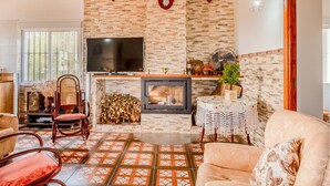 A cozy living room with a fireplace, a TV, and a seating area with a patterned floor. - Beautiful home in Alcolea del Rio (Alcolea del Rio)