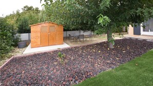 A wooden shed with two doors, surrounded by a garden with a mix of grass and gravel. - Amazing home in Avignon (Avignon)