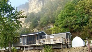 A lakeside cabin with a deck, a large window, and a small shed. - Waterfront River Home (Harpers Ferry)