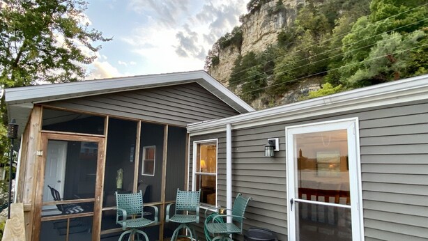 A small cabin with a deck, two chairs, a table, and a trash can. - Waterfront River Home (Harpers Ferry)