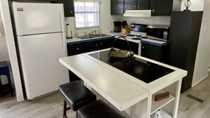 A compact kitchen with a central island, a refrigerator, a stove, and a sink. - Waterfront River Home (Harpers Ferry)