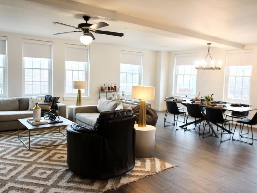 A spacious living room with a sofa, coffee table, and a dining area with chairs and a table.