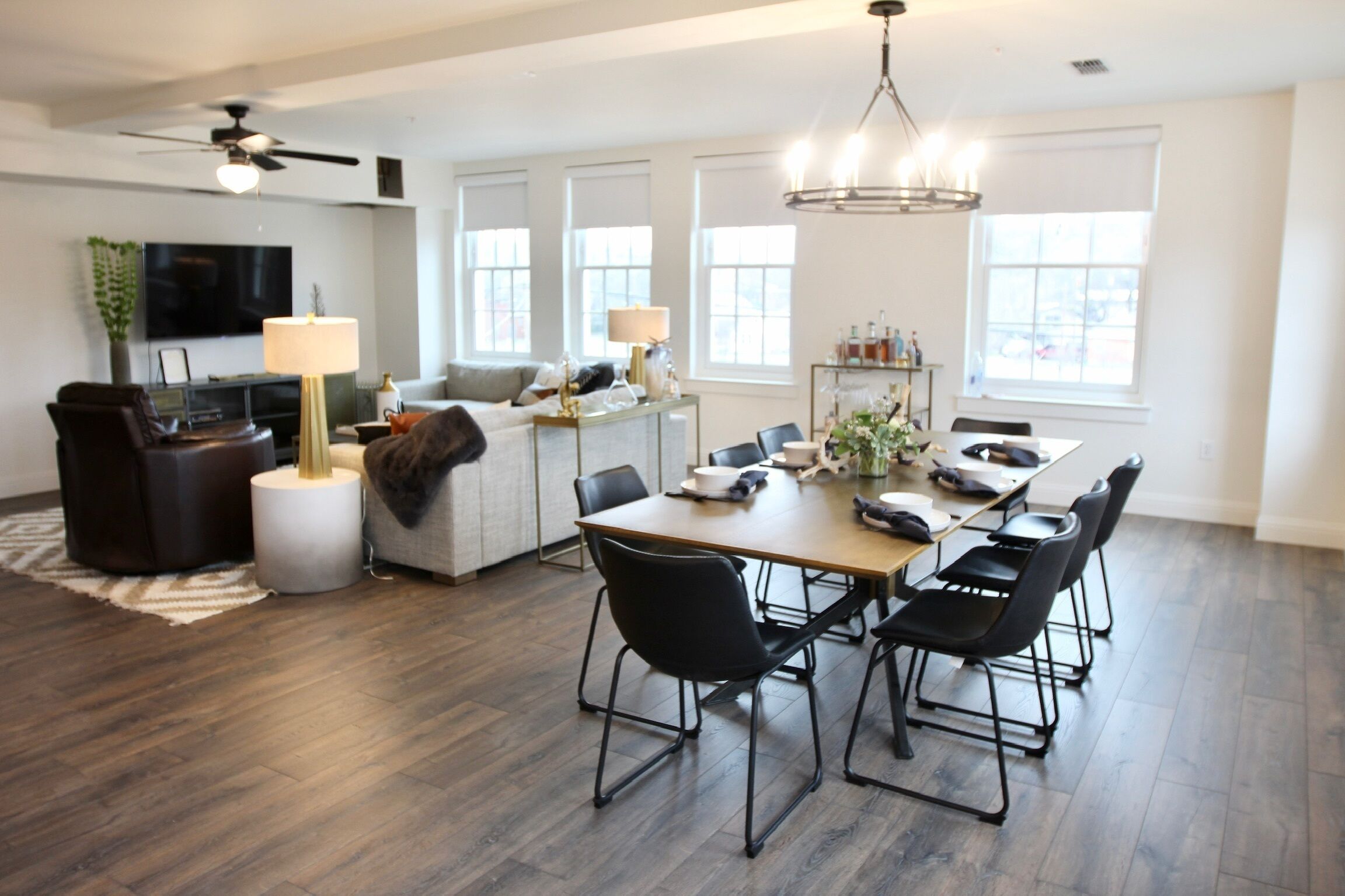 A modern living room with a sofa, coffee table, and TV. There is a dining area with a table and chairs.