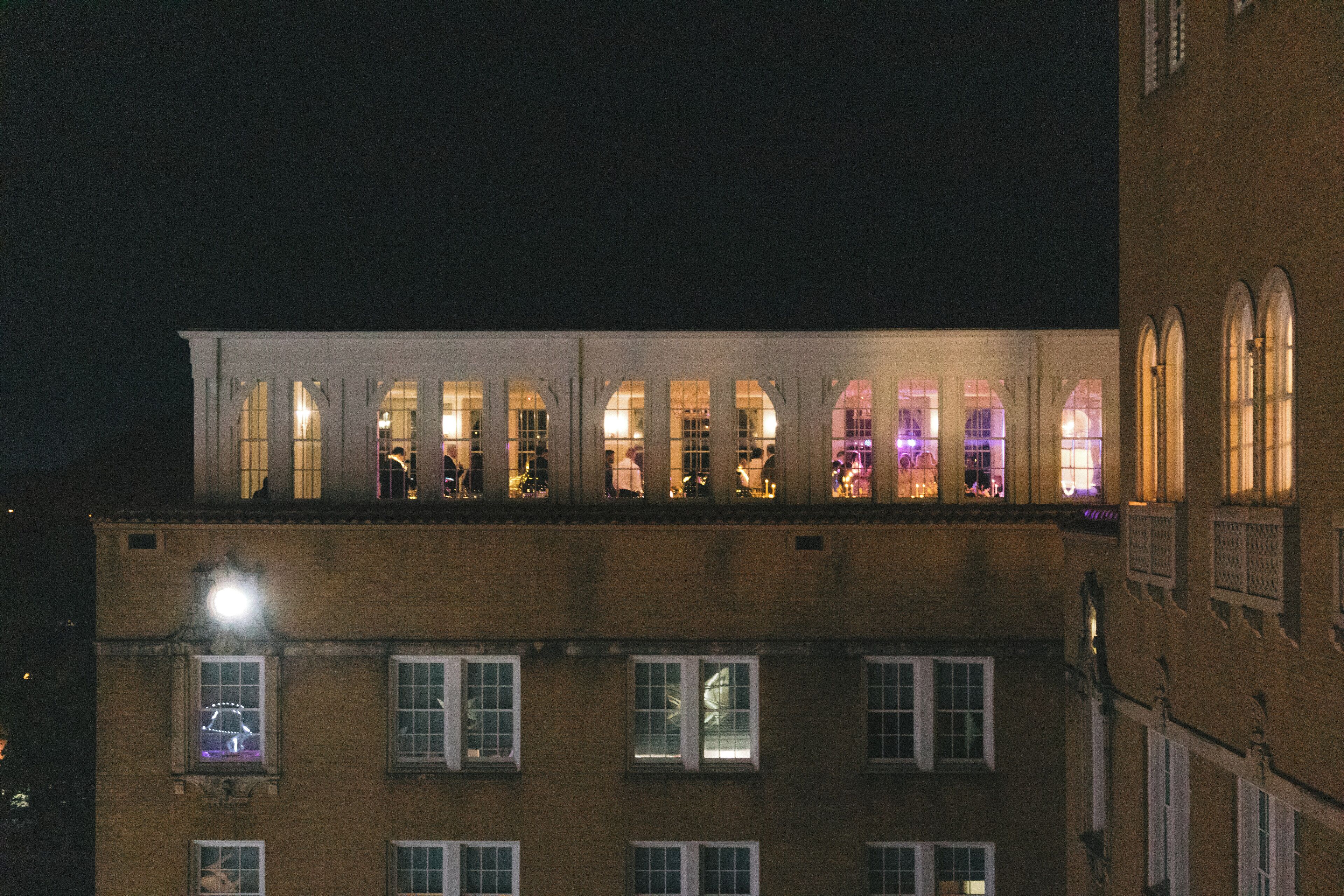 A building with multiple windows, some with lights inside, and a street lamp outside.
