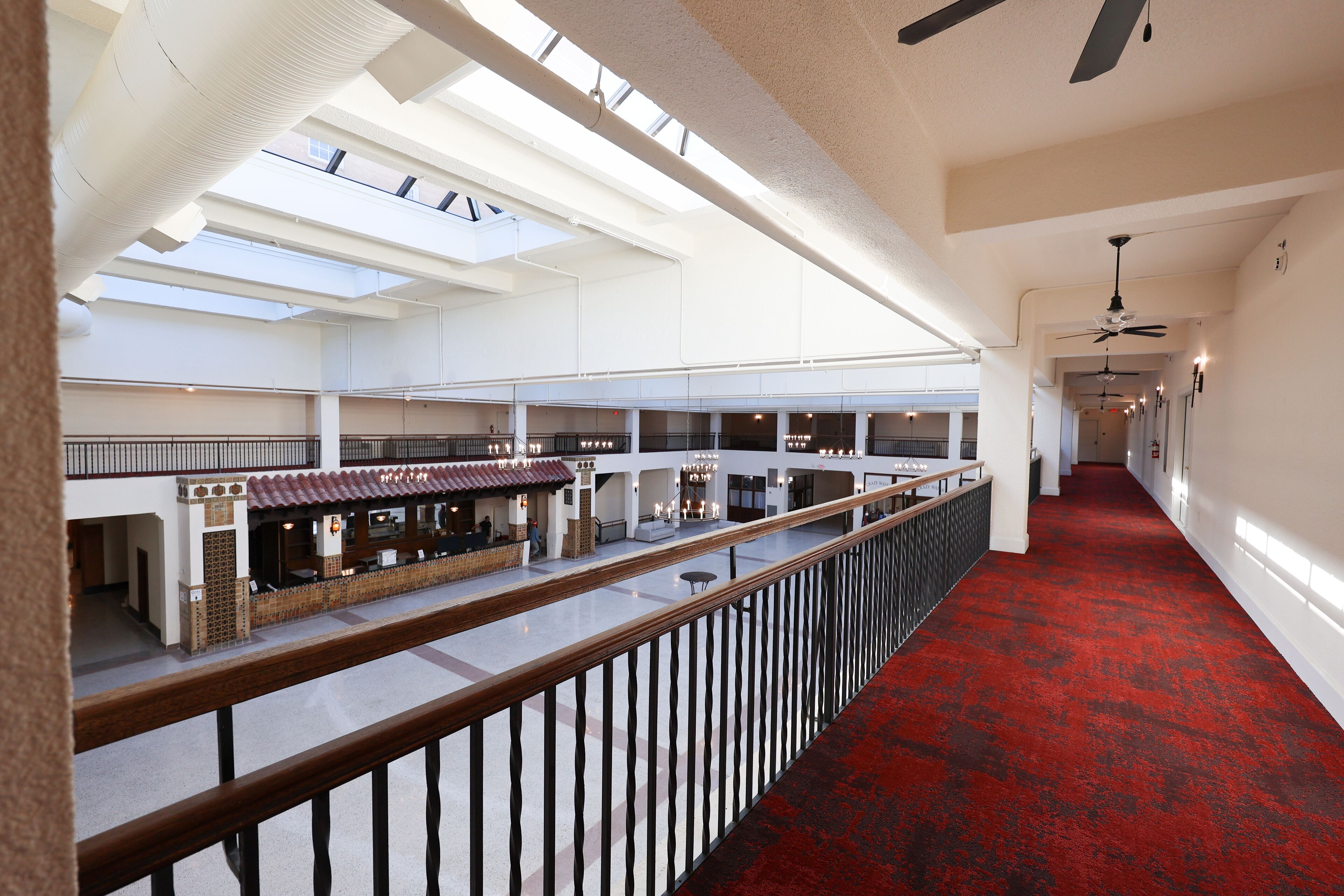 A spacious indoor area with multiple levels, a red carpeted corridor, and a restaurant with outdoor seating.