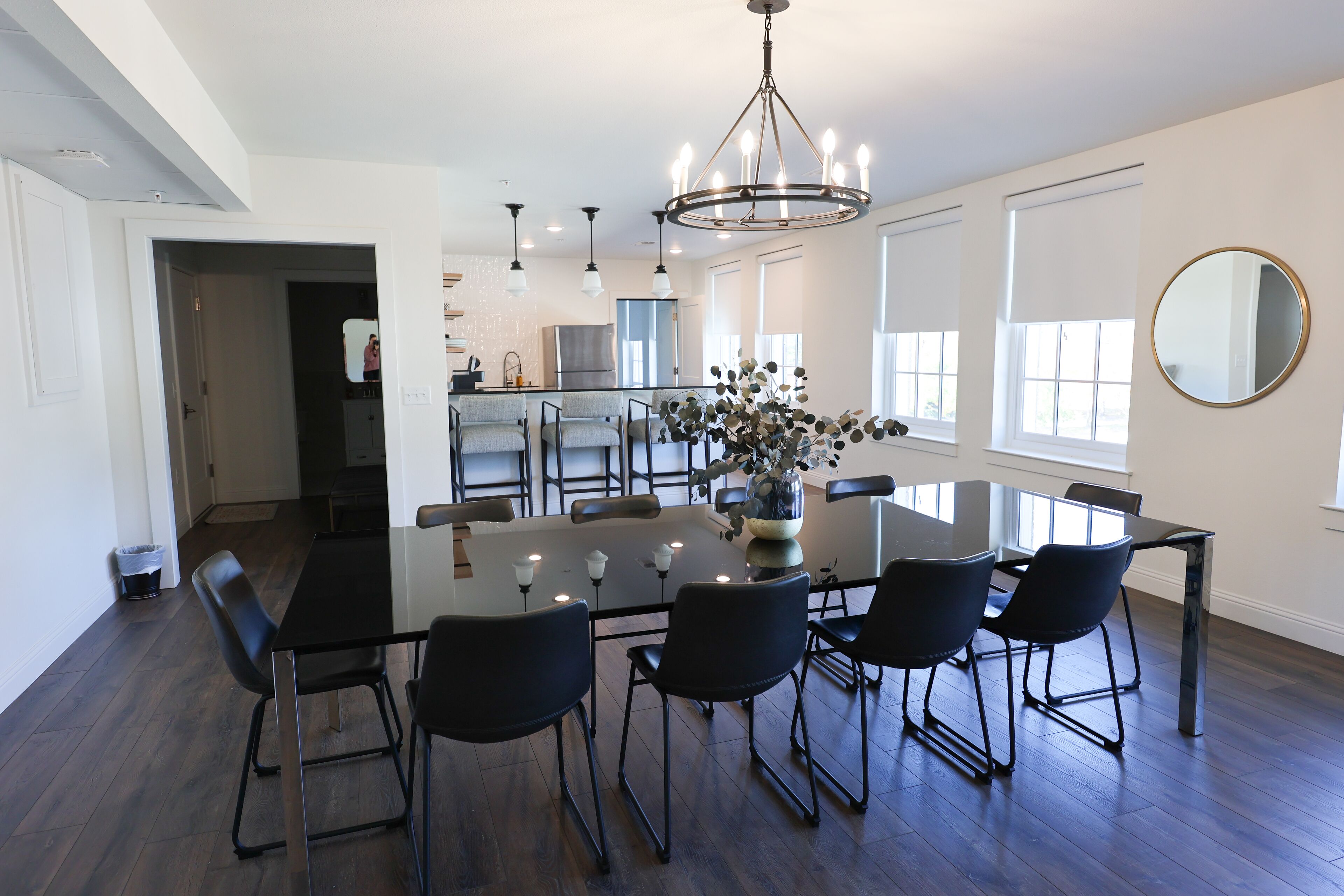A modern dining area with a glass table, black chairs, and a chandelier.