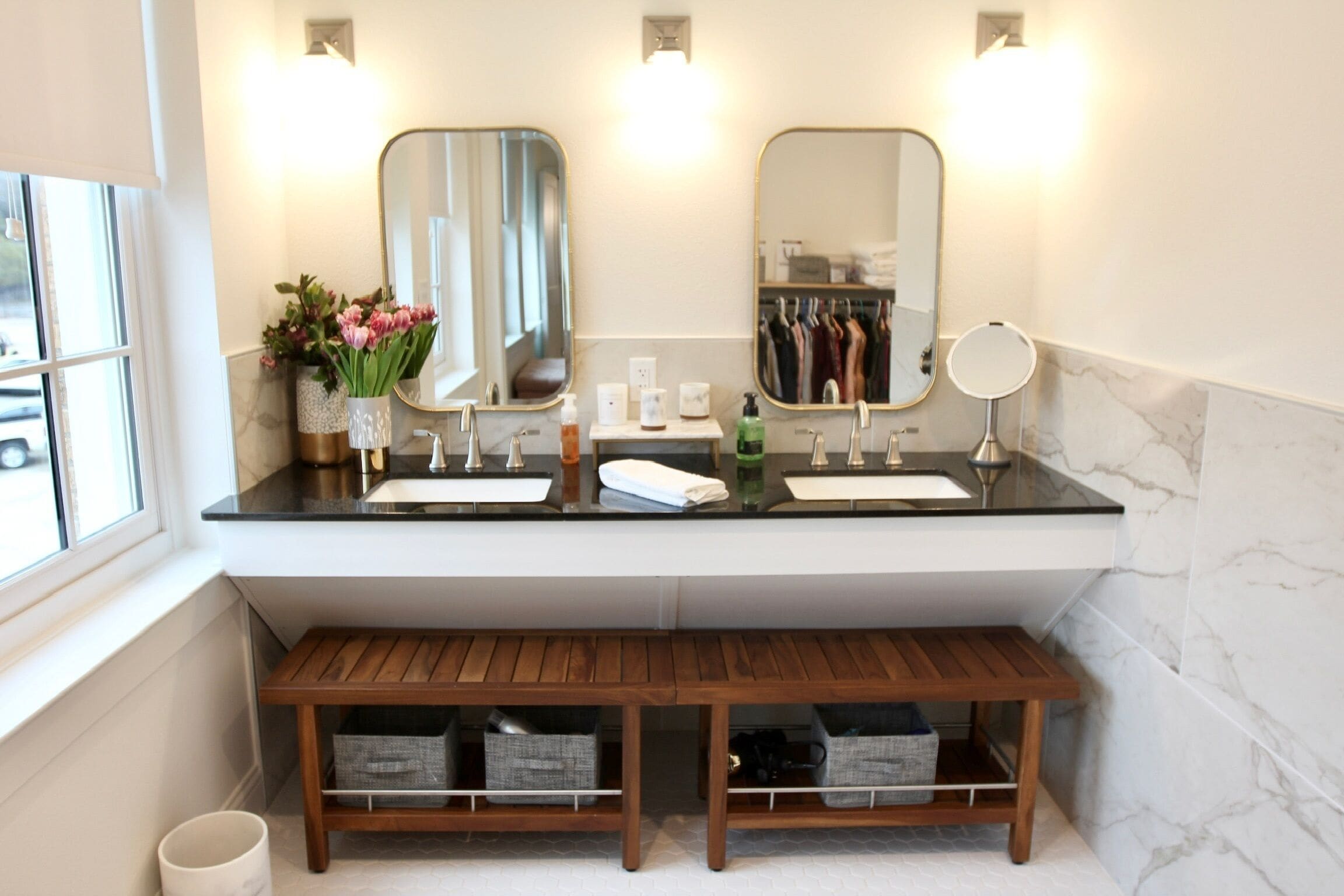 Un baño moderno con dos lavabos, un espejo sobre el mueble y un banco de madera.