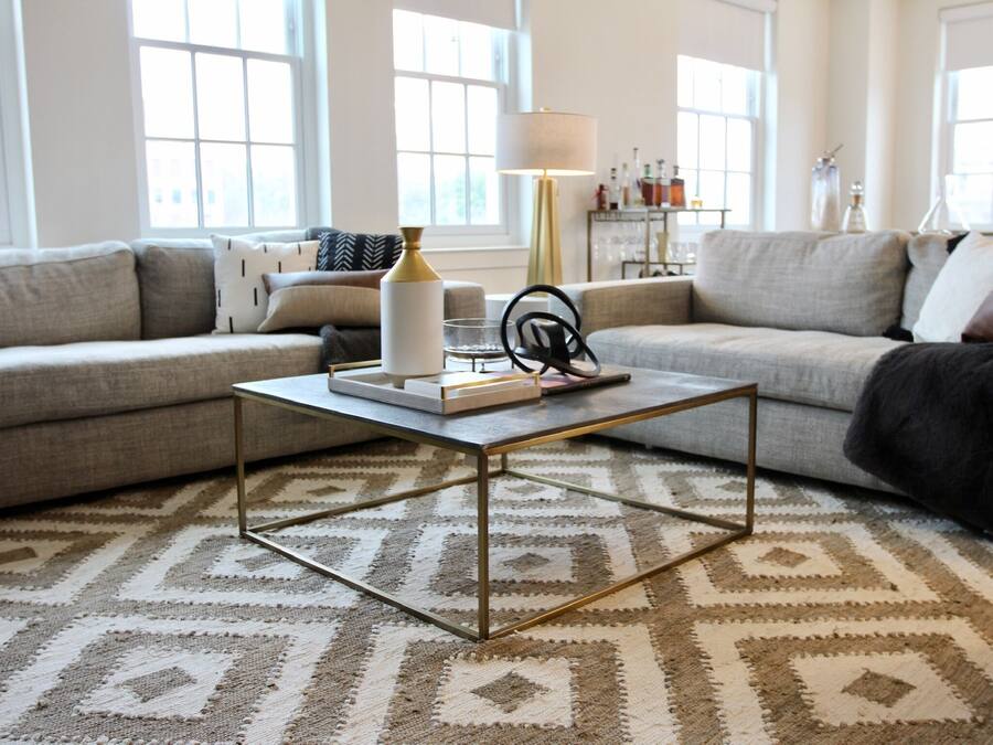 A modern living room with a patterned rug, a coffee table, and a sofa.