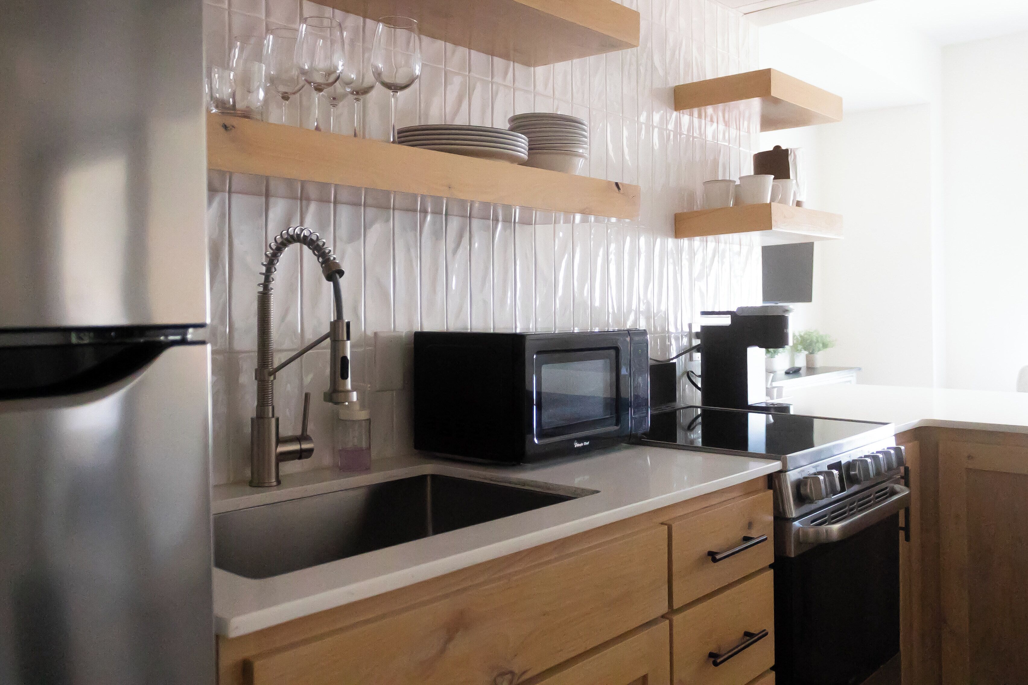 A modern kitchen with stainless steel appliances, wooden cabinets, and a white countertop.