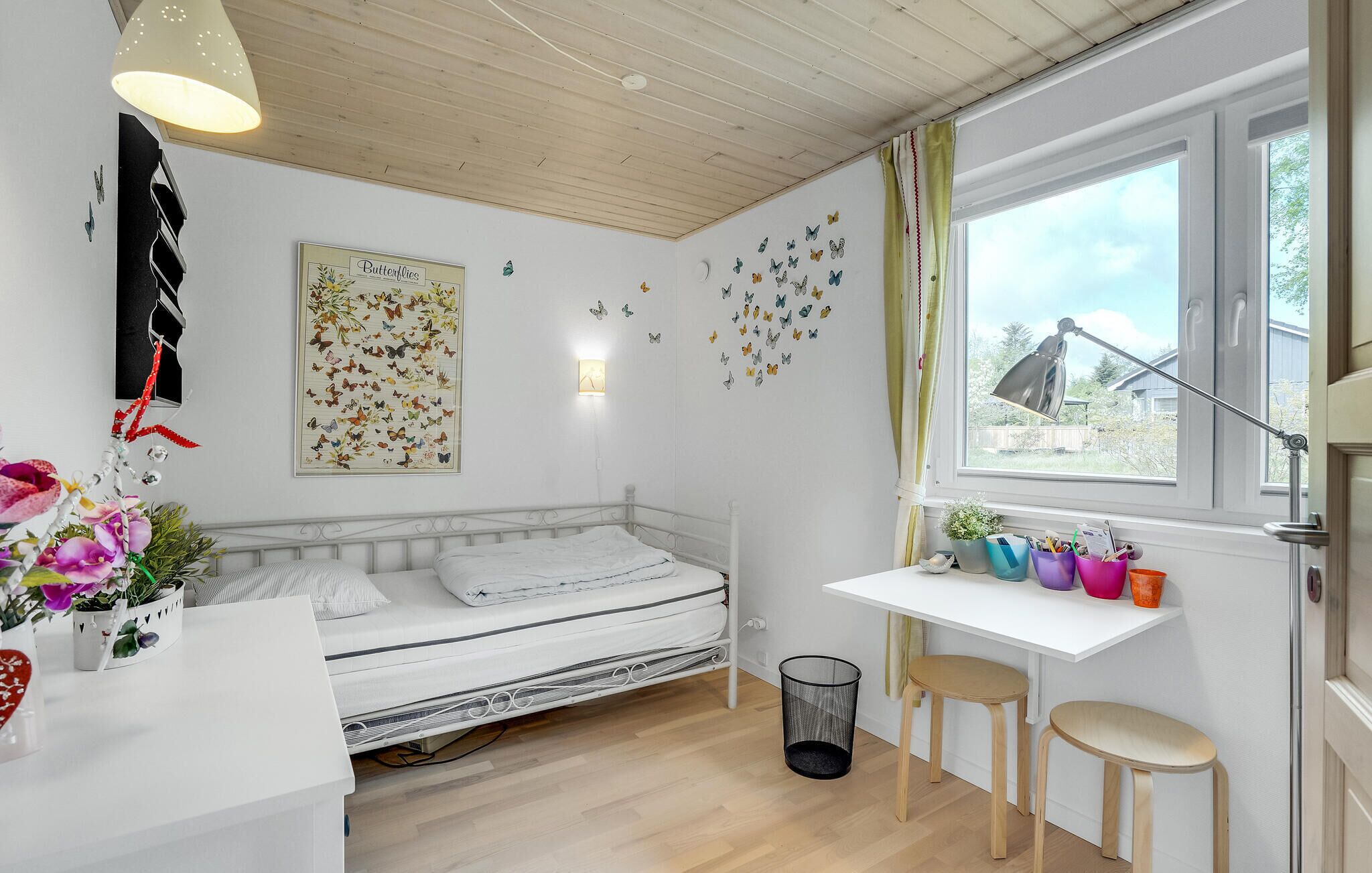 A bedroom with a bed, a desk, and a window.