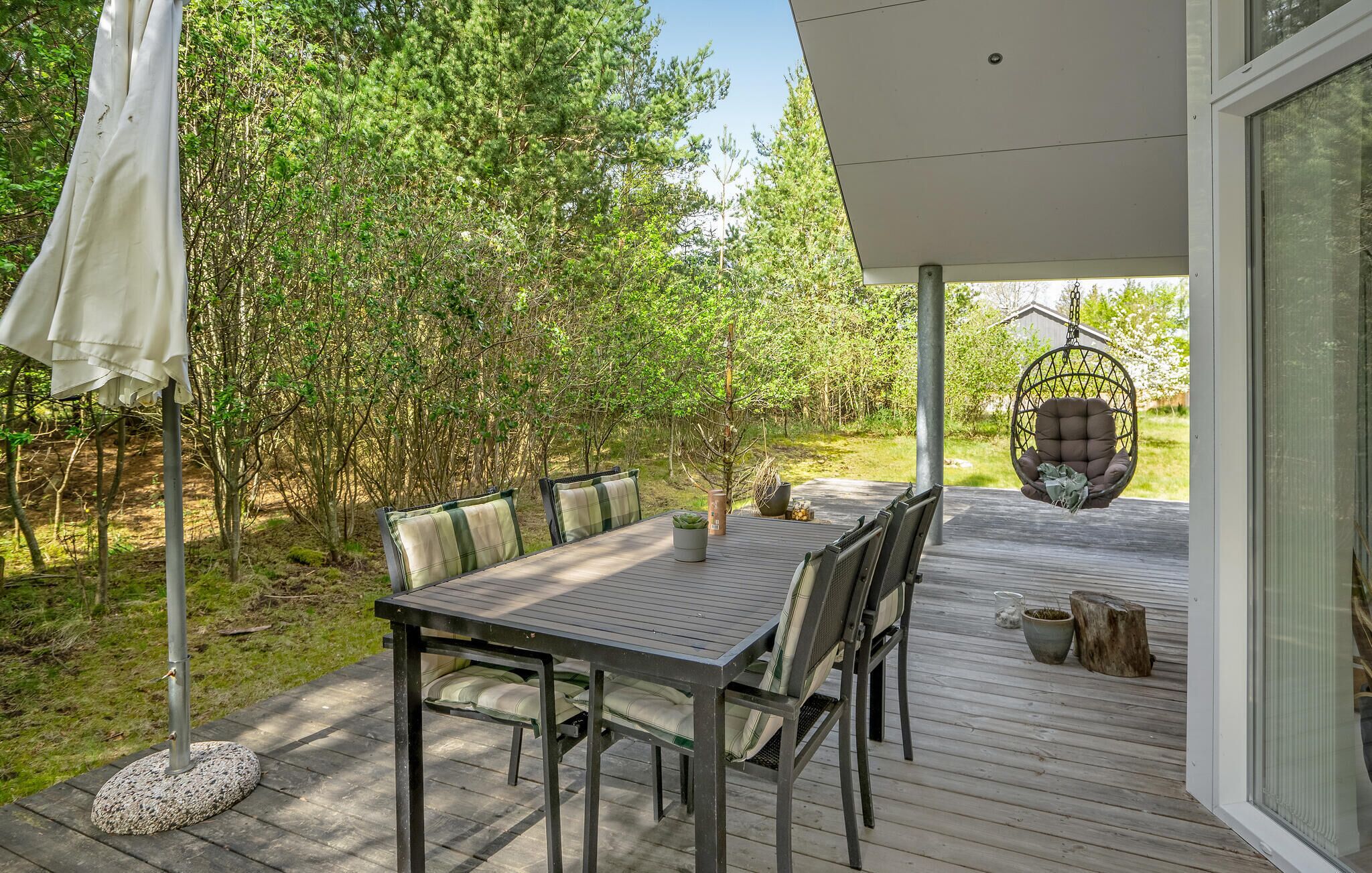 An outdoor patio with a table and chairs, surrounded by trees.