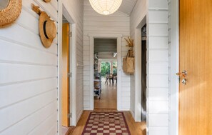 A hallway with white wooden walls, a checkered rug, wicker baskets, and a hanging bag. - Gorgeous home in Hadsund with WiFi (Hadsund)