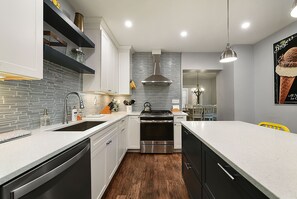 Una cocina moderna con estufa de acero inoxidable, pileta doble y salpicadero con azulejos.