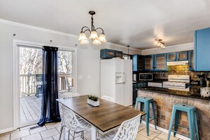 A kitchen with a wooden table and white chairs, blue cabinets, and a stone backsplash. - Large 4 Bed + Bonus Room-3 Full Baths-Sleeps 9 (Wichita)
