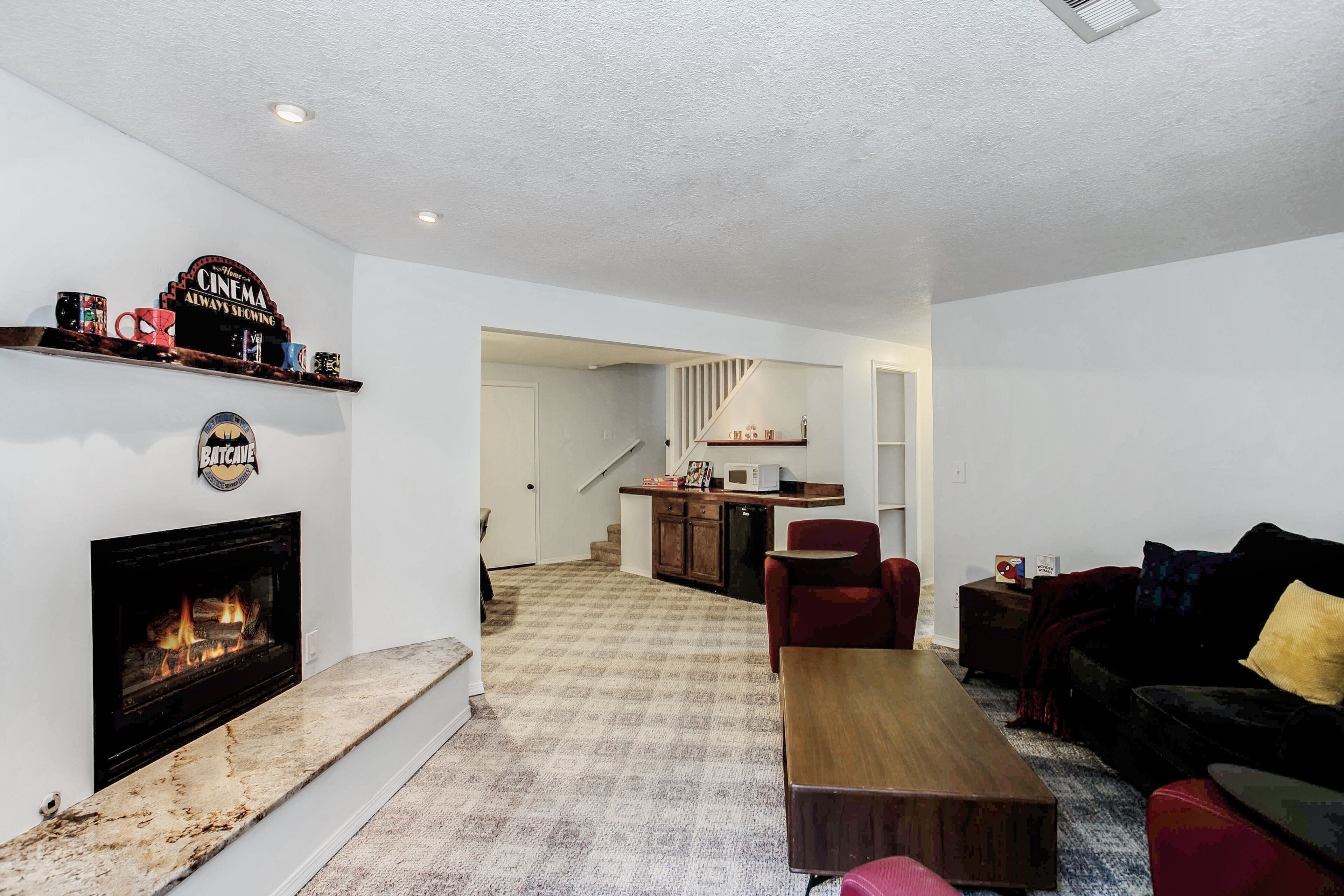 A living room with a fireplace, a staircase leading to a kitchen, and a cozy seating area.