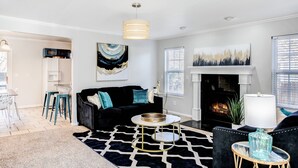 A modern living room with a black sofa, a round coffee table, and a fireplace. - Spacious 2,500 Sq Ft Wichita Home -3 Showers-2 Tubs-Near Base & Arena (Wichita)