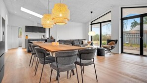Une cuisine moderne avec des meubles de couleur sombre, une table à manger en bois et une grande fenêtre.