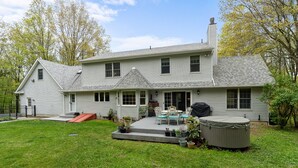 Une maison à deux étages dotée d’un patio, d’un espace salon extérieur et d’un jacuzzi.