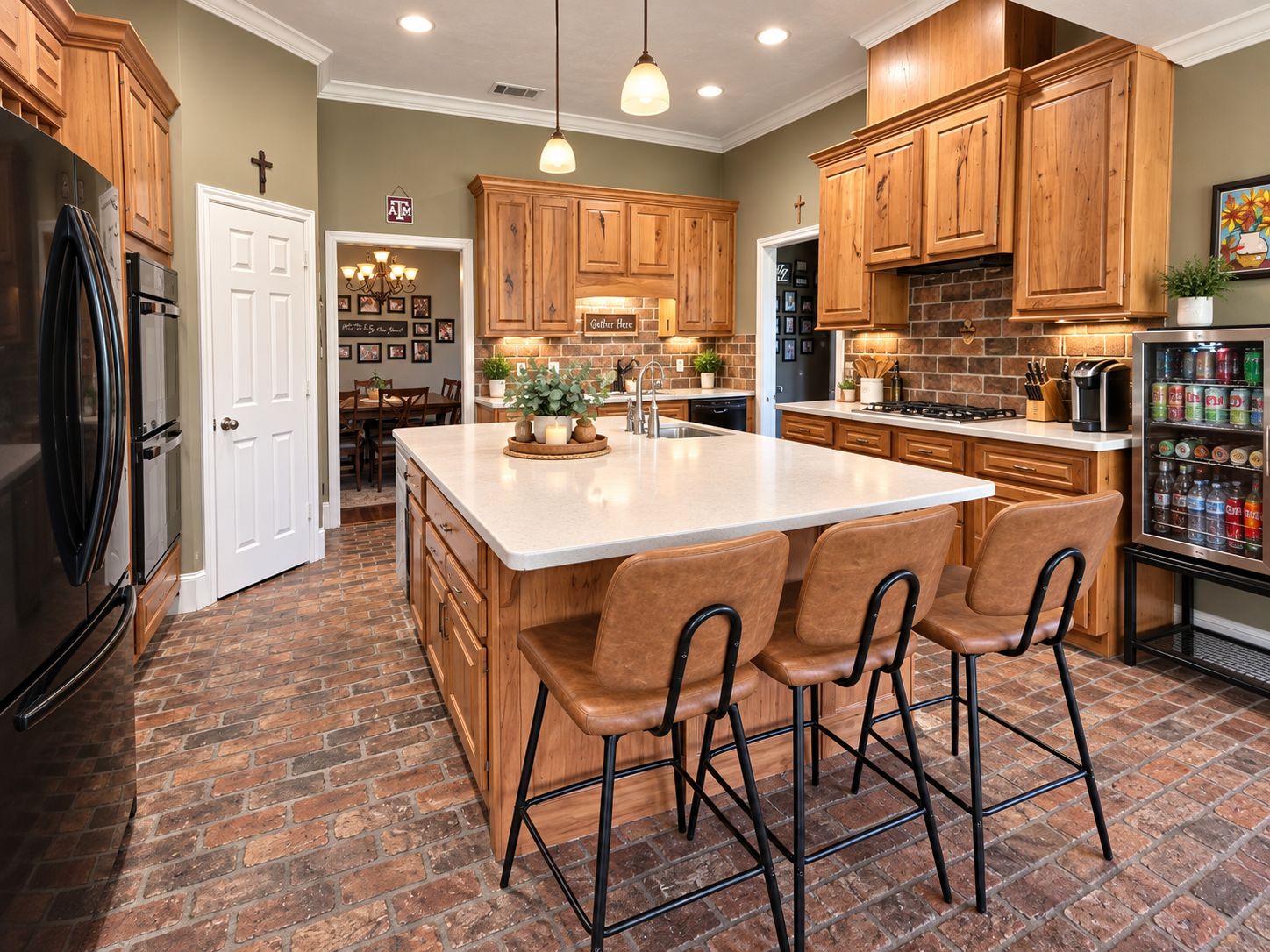 A kitchen with wooden cabinets, a central island with bar stools, a refrigerator, and a beverage refrigerator.