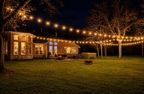 Una casa de ladrillo con patio, luces colgantes y un jacuzzi.