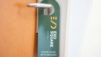 A hotel room door with a keycard holder displaying the Exo Square Hotel logo and a "Please clean" instruction.