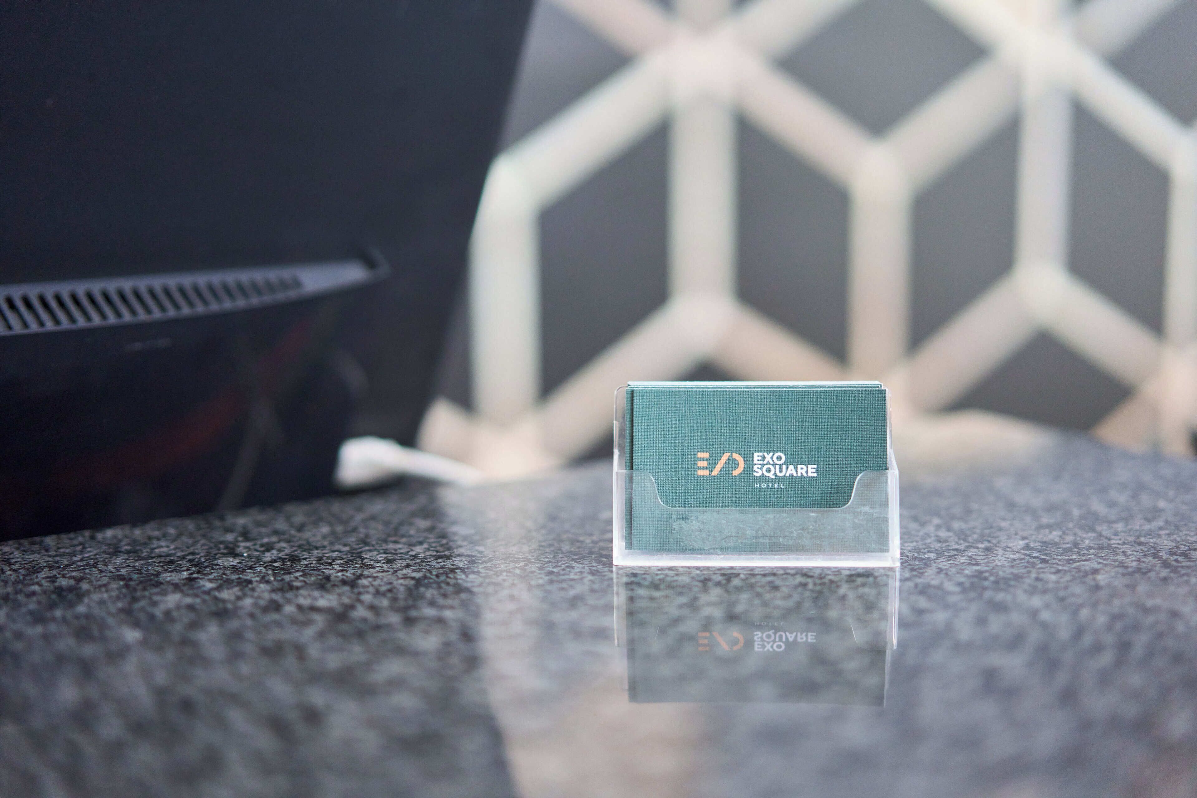 A hotel card for EXO SQUARE HOTEL on a clear stand.