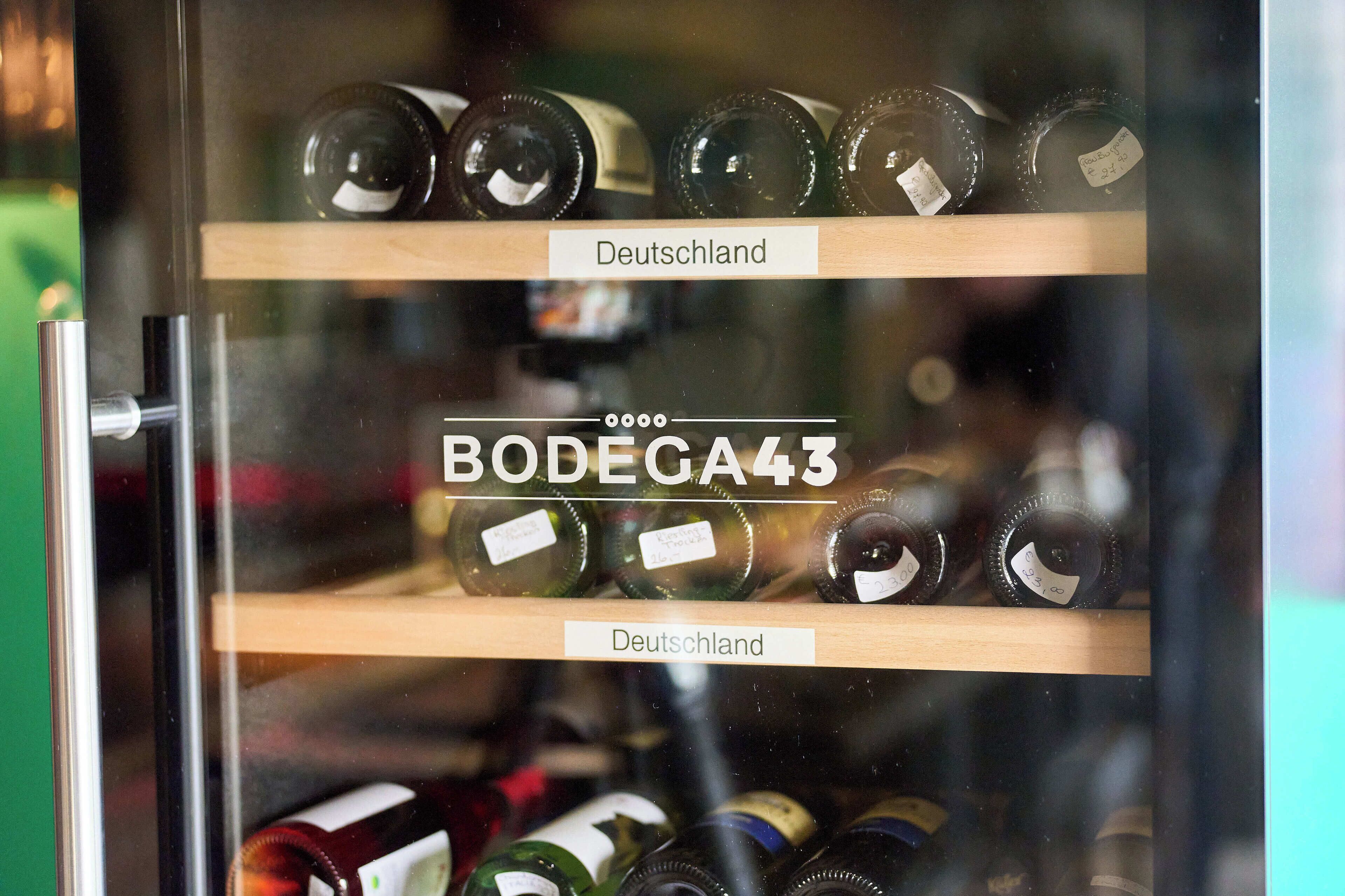 Ein Weinkühler mit Flaschen, beschriftet mit 'Deutschland' und 'BODEGA43'.