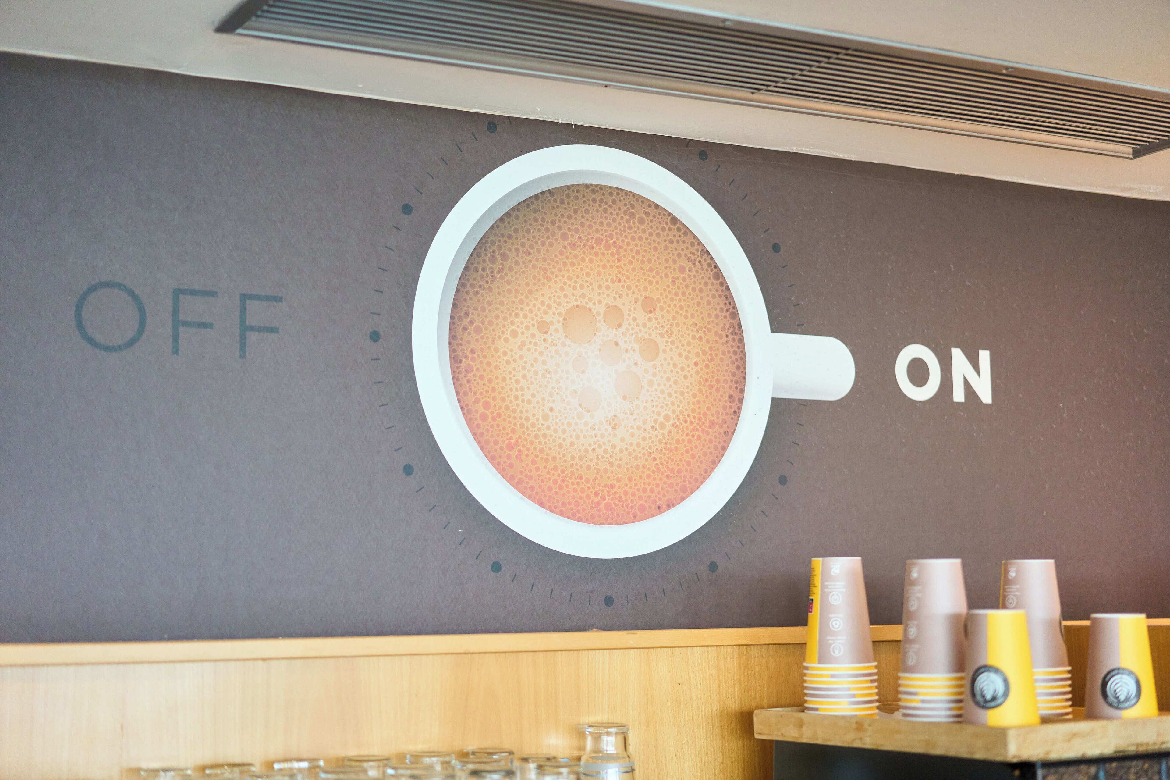 Un mur orné d’un motif représentant une tasse de café, avec les mots « OFF » et « ON » de part et d’autre.