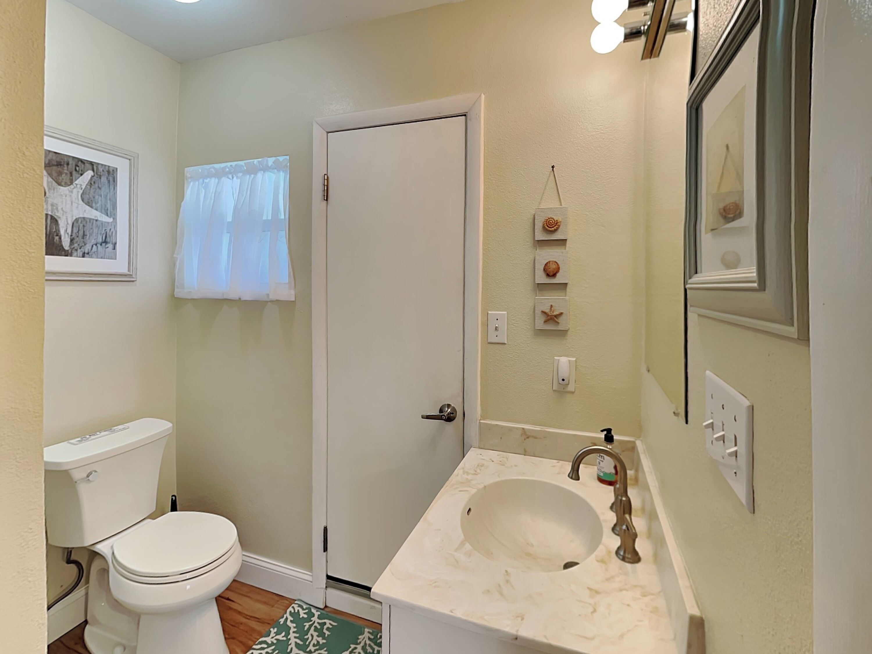 Une salle de bain comprenant des toilettes, un lavabo et une porte donnant sur une autre pièce.
