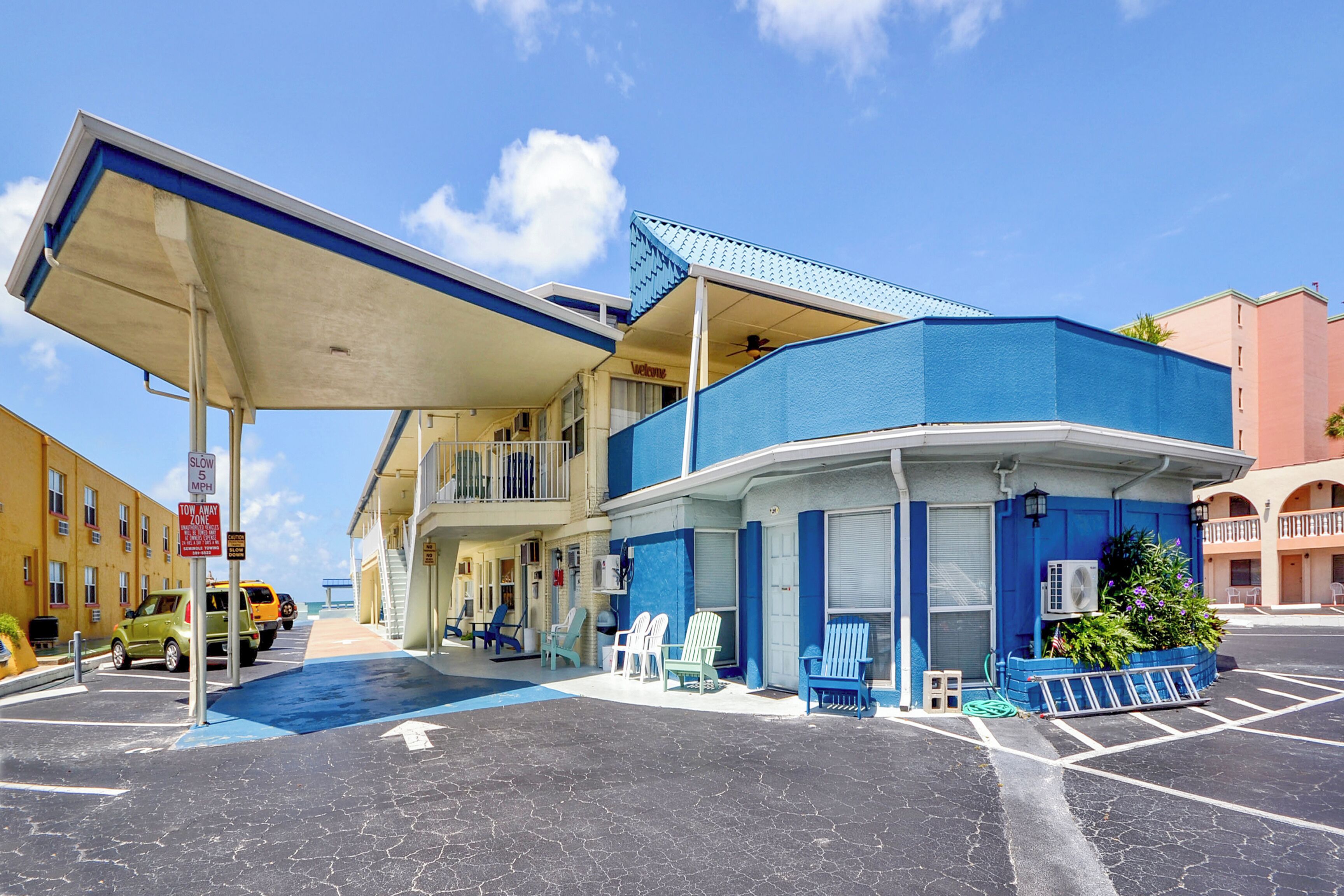 A motel with a blue and white exterior, a gas station, and outdoor seating.