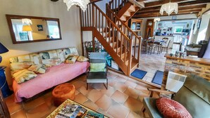 A cozy living room with a sofa, a wooden staircase, and a dining area with chairs and a table. - 2 bedroom gorgeous home in Concarneau (concarneau)