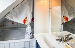 Ein Badezimmer mit einer Badewanne, einem weißen Waschbecken und einem Spiegel.