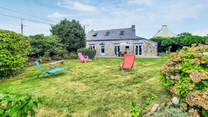 A stone house with a sloped roof, a patio with outdoor furniture, and a well-maintained garden. - 2 bedroom gorgeous home in Concarneau (concarneau)
