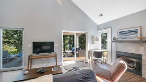 A spacious living room with a television, a fireplace, and a ceiling fan.