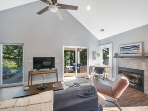 Uma sala de estar ampla com televisão, lareira e ventilador de teto.