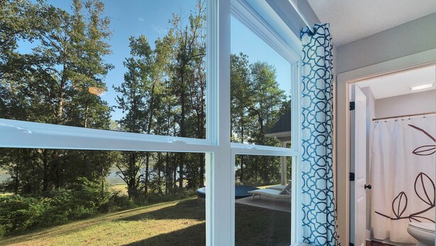 A room with a large window overlooking a grassy yard and trees.