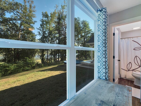 Quarto com uma grande janela com vista para um gramado e árvores.