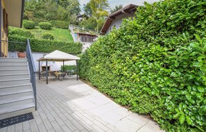 A covered outdoor seating area with a table and chairs, a staircase, and a well-maintained hedge. - Pet friendly home in Voiandes Tremosine (Voiandes Tremosine)