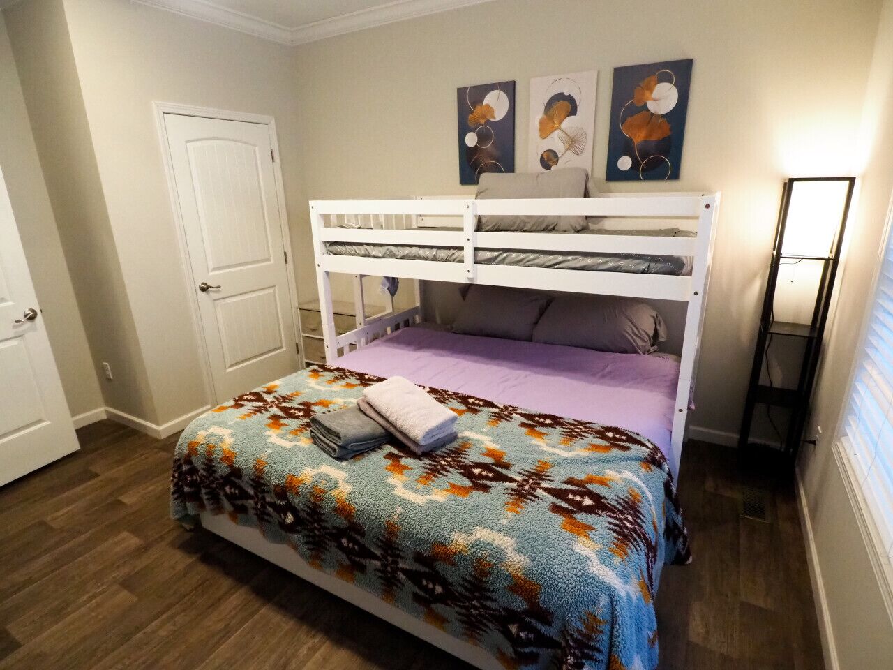 Ein Schlafzimmer mit einem Etagenbett, einer gemusterten Bettdecke und zwei Wandbildern.