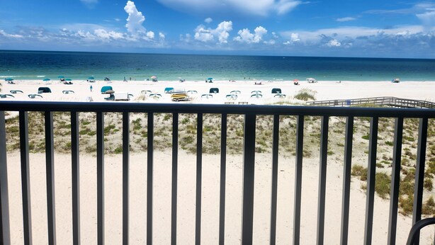 Blick auf den Strand vom Balkon mit Geländer, feiner Sand und Meer.