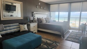 Ein Schlafzimmer mit einem Bett, einem Fernseher, einem Nachttisch und Meerblick.