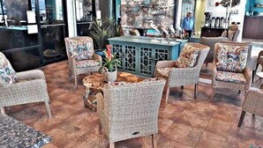 Eine Lobby mit Korbmöbeln, einem zentralen Couchtisch und einem großen abstrakten Gemälde.