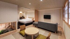 Ein modernes Hotelzimmer mit Bett, Sofa und Esstisch.