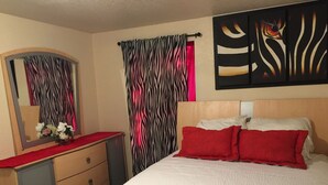 Un dormitorio con cama, cómoda, espejo y cortinas a rayas de cebra.