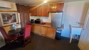 Una cocina compacta con armarios de madera, un refrigerador, un microondas y una mesa de comedor con sillas.