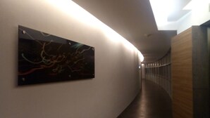 Un couloir au design moderne, avec un plancher foncé et une œuvre d’art abstraite accrochée au mur.