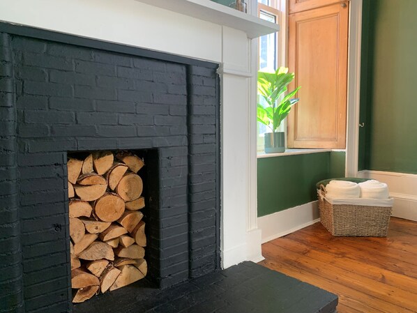 Ein modernes Wohnzimmer mit Kamin aus schwarzem Backstein, Holzboden und grüner Wand.