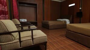 Una habitación de hotel con cama, dos sillones, un sofá, televisión y armario.