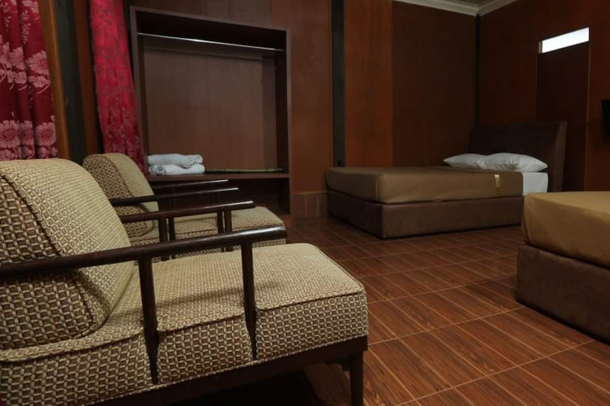 Een hotelkamer met een bed, twee fauteuils, een bank, een televisie en een kledingkast.